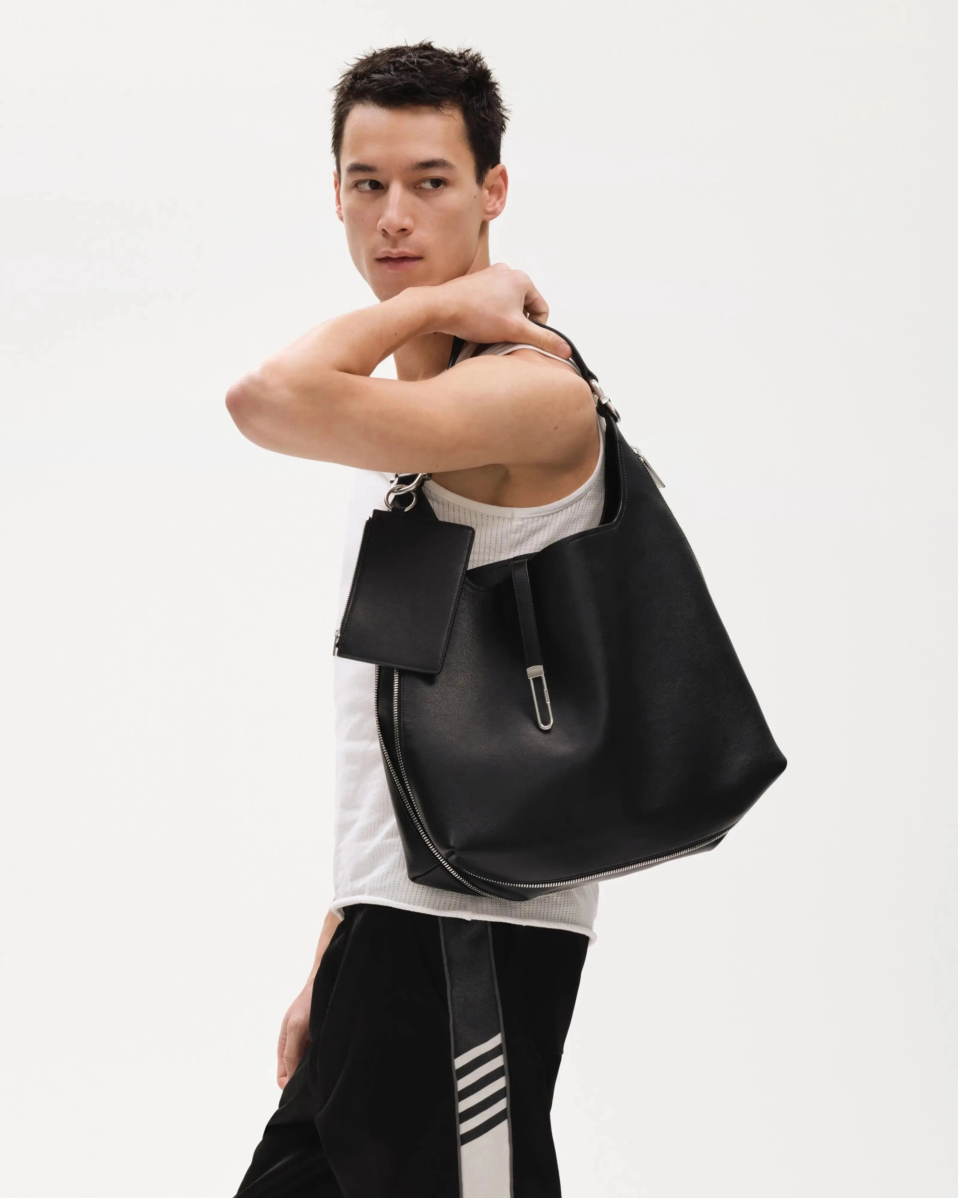 Male-Model-holding-TAD-FAB-Zip-Hobo-matte-black-calfskin-shoulder-bag