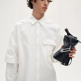 Model-holding-TAD-FAB-Softie-Mini-matte-black-calfskin-shoulder- bag-with-silver-tone-carabiner-style-buckle